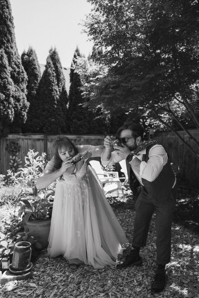 Bride and groom shotgun beers during their garden party wedding